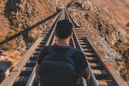 man carrying backpack while standing in the middle of railway in Matucana Peru