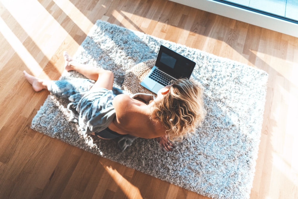 topless woman using MacBook Pro on floor