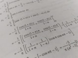 A page filled with mathematical formulas and integrals, featuring symbols and trigonometric functions such as cos and sin. The text is printed in black on an off-white background, with a slight angle giving a dynamic effect to the layout.