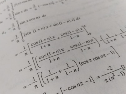 A page filled with mathematical formulas and integrals, featuring symbols and trigonometric functions such as cos and sin. The text is printed in black on an off-white background, with a slight angle giving a dynamic effect to the layout.
