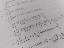A page filled with mathematical formulas and integrals, featuring symbols and trigonometric functions such as cos and sin. The text is printed in black on an off-white background, with a slight angle giving a dynamic effect to the layout.