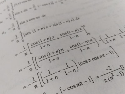 A page filled with mathematical formulas and integrals, featuring symbols and trigonometric functions such as cos and sin. The text is printed in black on an off-white background, with a slight angle giving a dynamic effect to the layout.