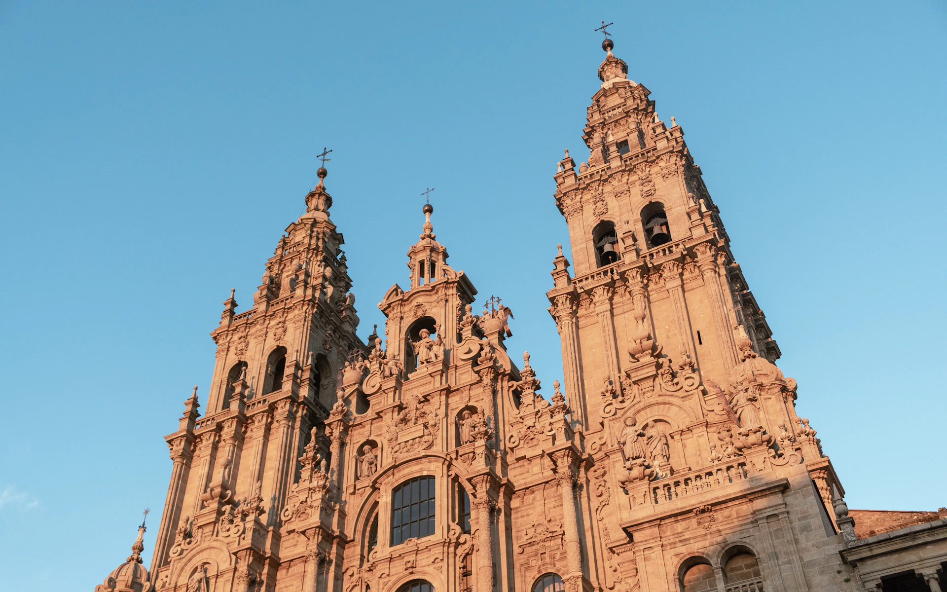 The intricate facade of Orvieto Cathedral, showcasing its detailed mosaics and gothic spires against a bright blue sky.