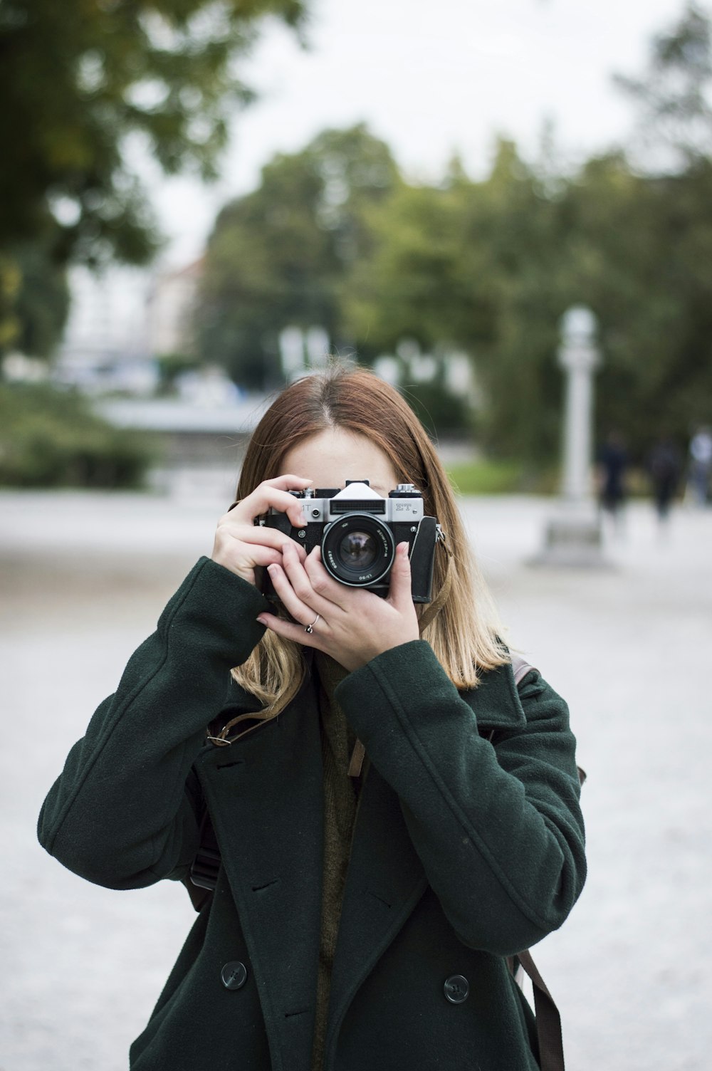 woman using SLR camera near trees during day