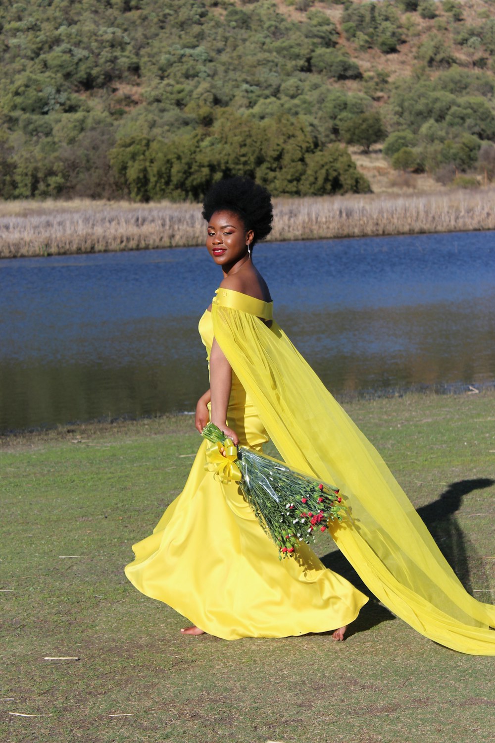 a woman in a yellow dress is walking by the water