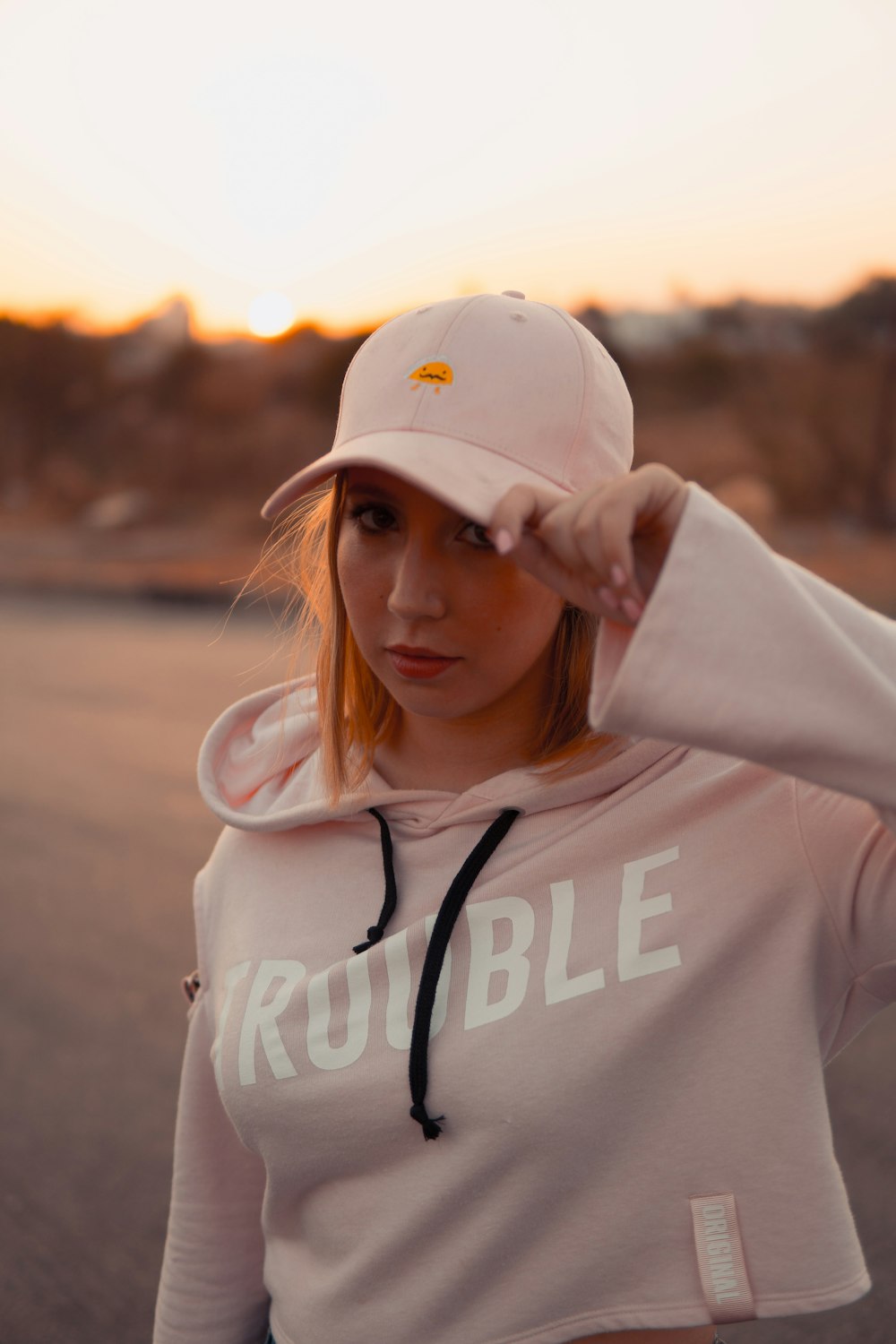 woman wearing pink Trouble hoodie and pink baseball cap
