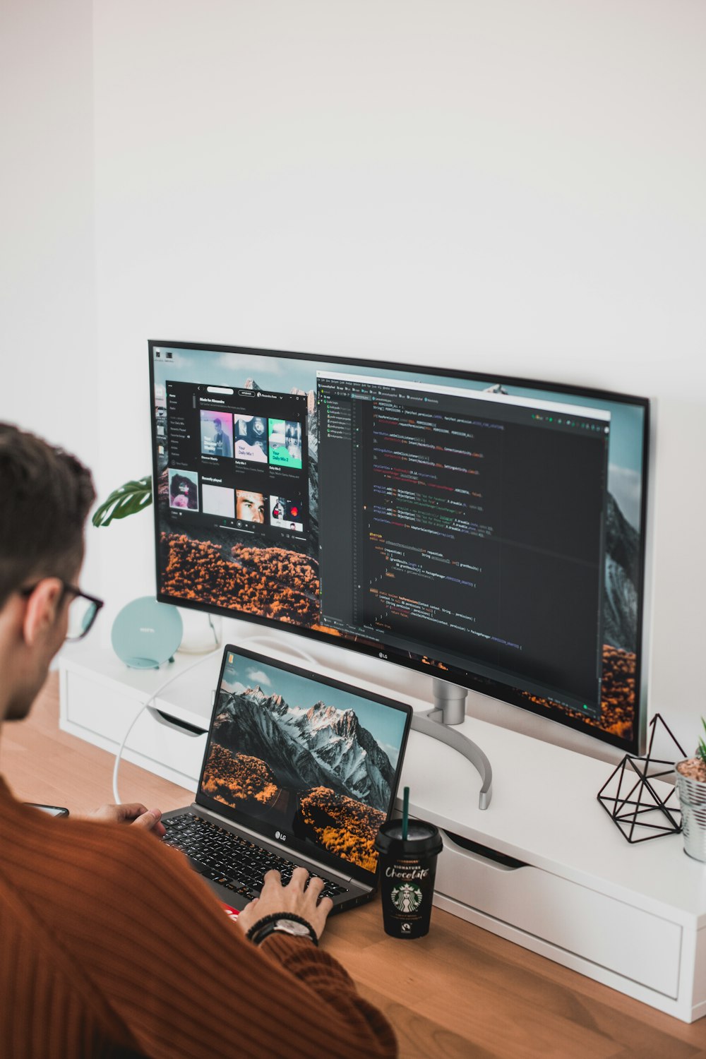 Hombre usando computadora portátil y monitor de computadora