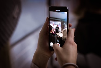 A close-up of hands recording a speaker on a smartphone at an event.