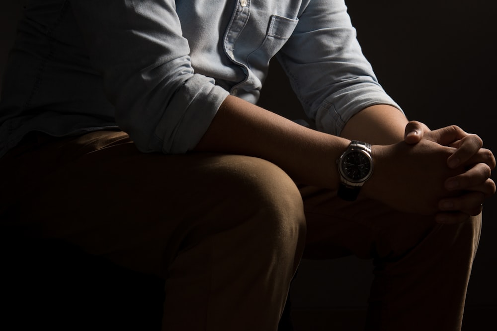 person wearing blue chambray dress shirt and brown bottoms