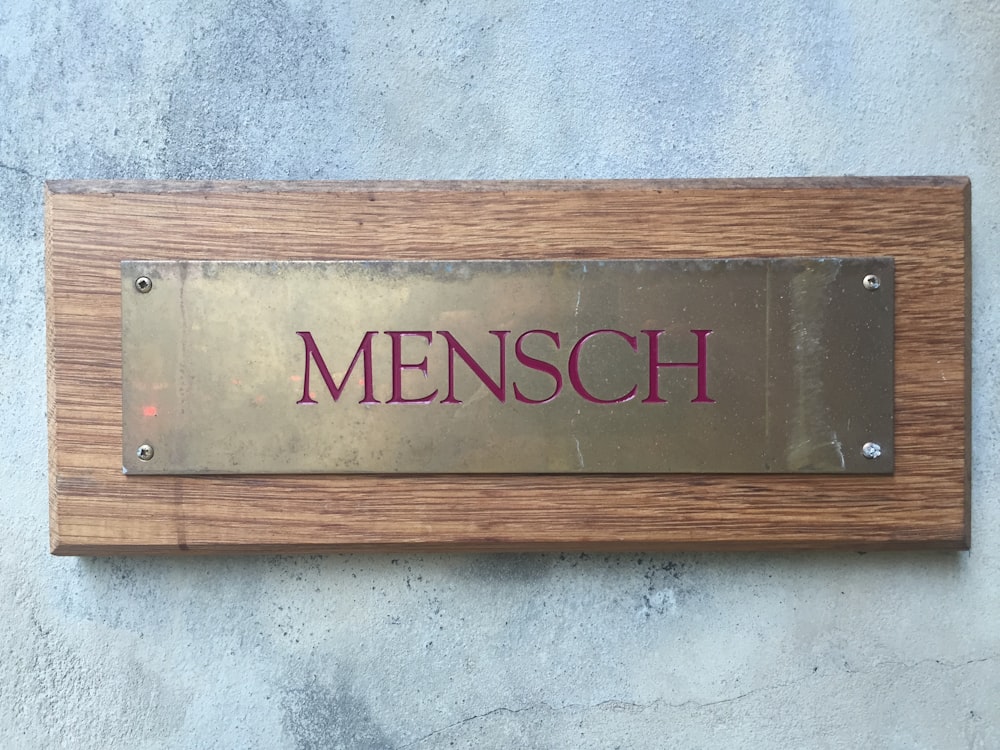 Mensch brass plate on wood block posted on wall