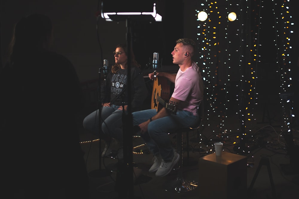 man and woman sitting side by side in front of microphones