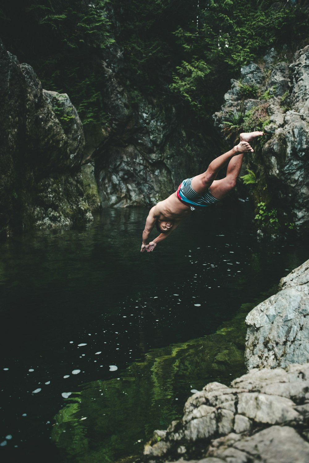 man wearing blue boardshorts dived on river