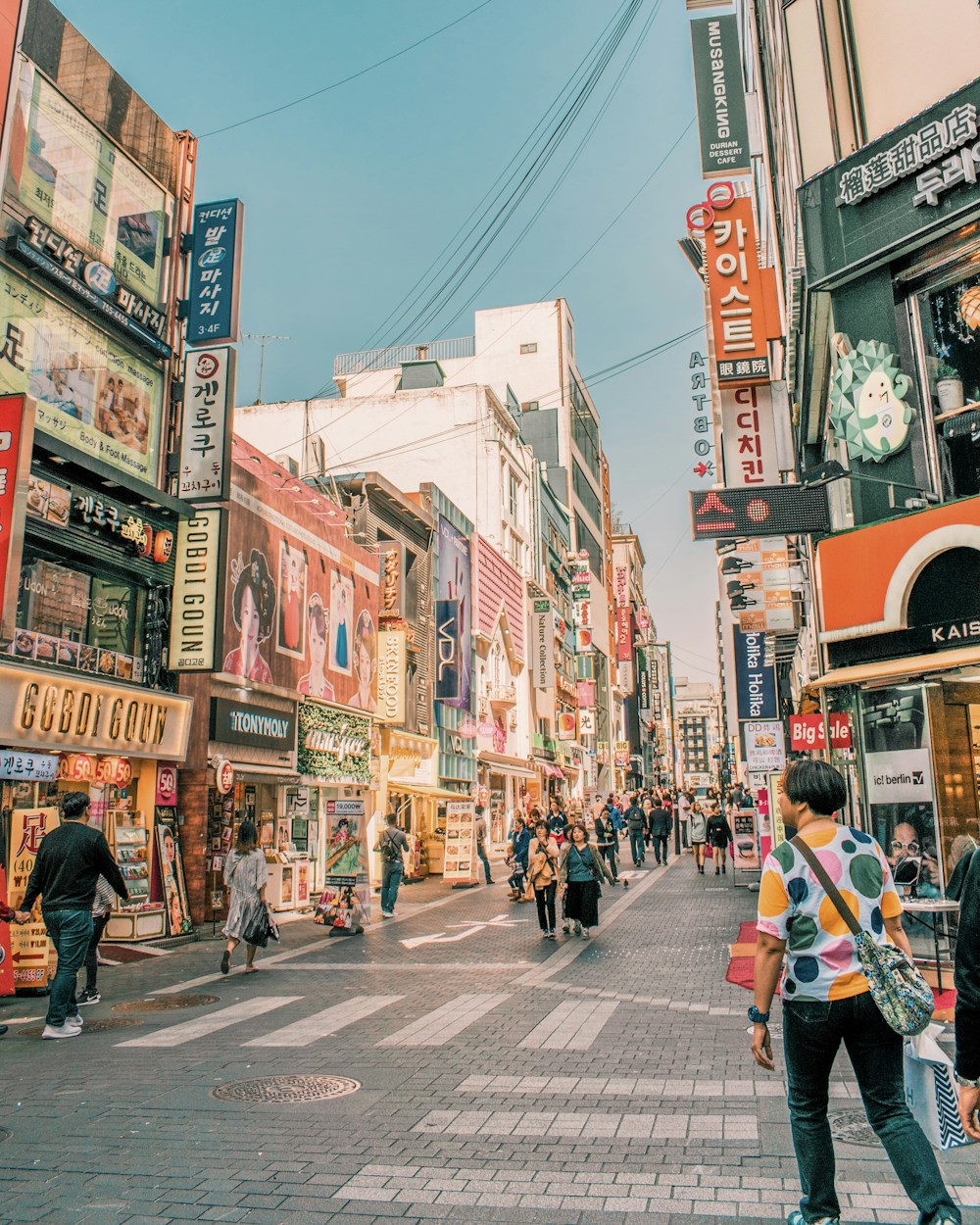 People walking a Seoul street between tall buildings