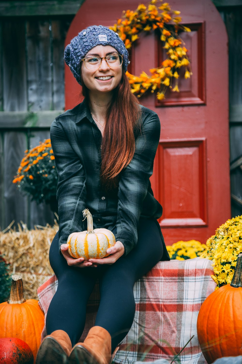 smiling woman sitting and holding orange pumpkin