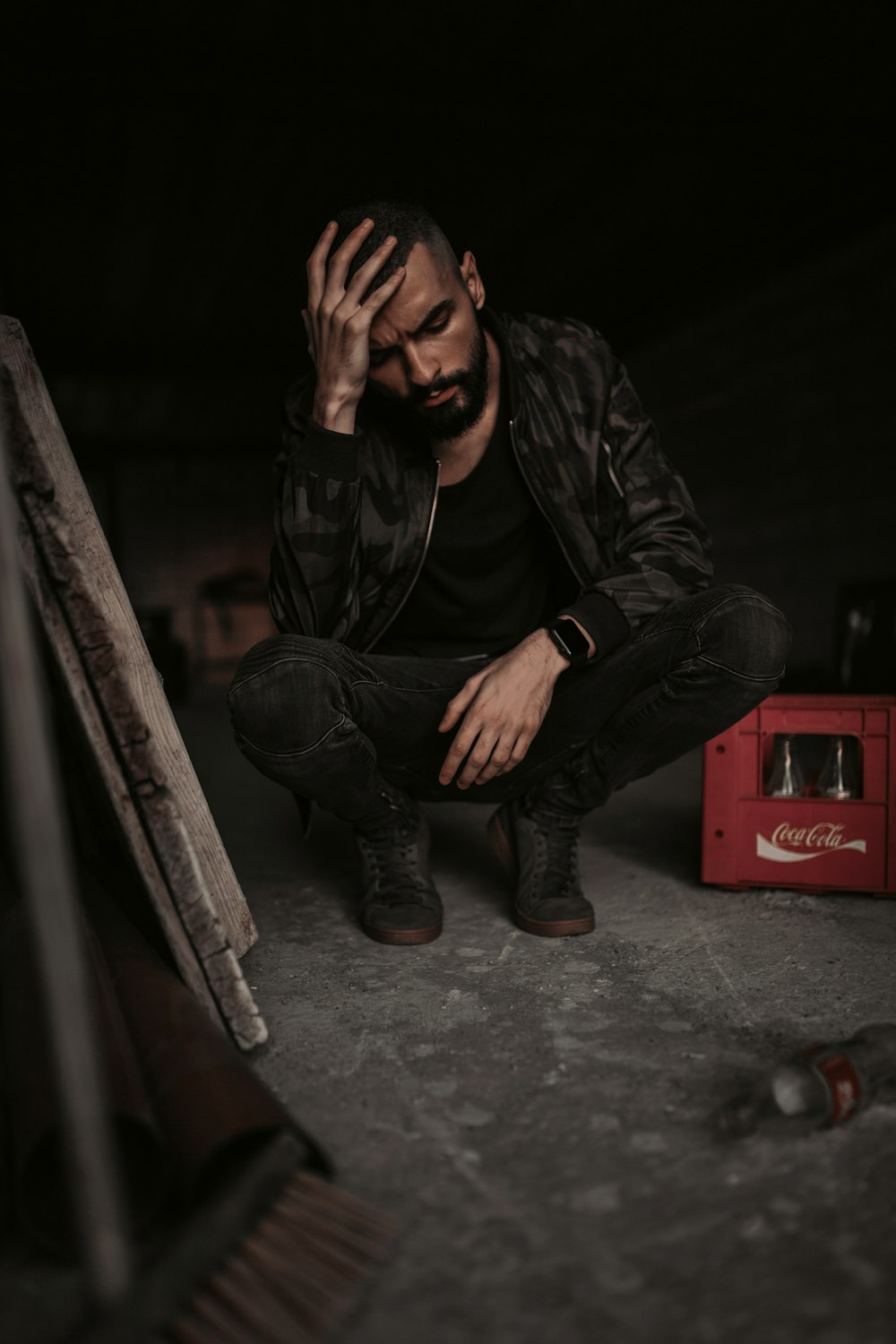 man sitting beside Coca-Cola plastic crate