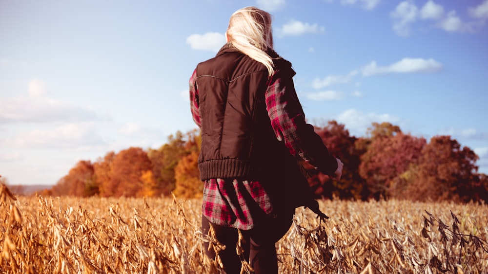 woman in black jacket standing on brown grass field during daytime