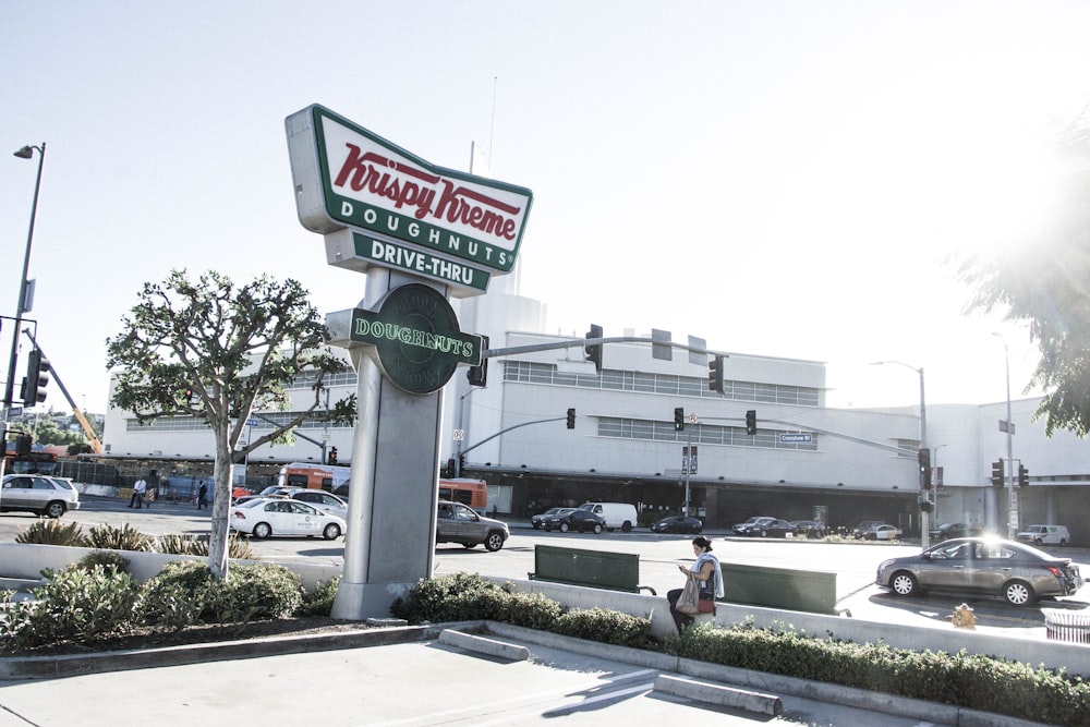 woman sitting near Krispy Kreme signage