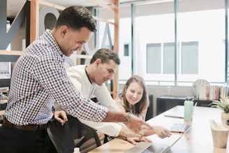 A friendly team of finance professionals collaborating around a laptop in a modern office.