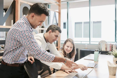 A friendly team of finance professionals collaborating around a laptop in a modern office.