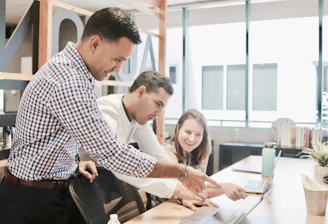 A diverse team collaborating over documents and laptops in a bright office space.
