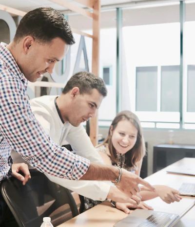 A diverse team collaborating over documents and laptops in a bright office space.