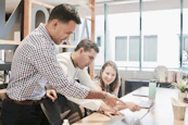 A friendly team of professionals collaborating over laptops in a bright office space.