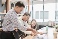 A team collaborating over project plans with charts and laptops in a bright office.