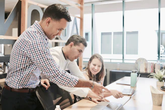 A friendly team of professionals collaborating over laptops in a bright office space.