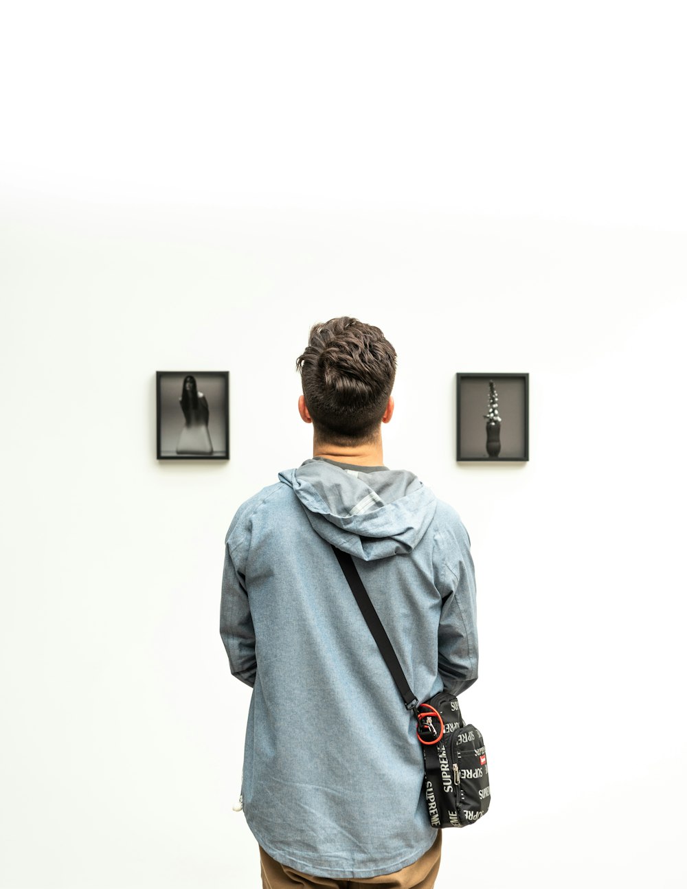 man wearing hoodie looking at artworks