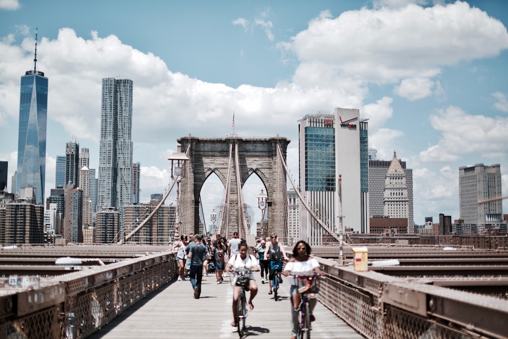 people biking and walking on bridge at daytime