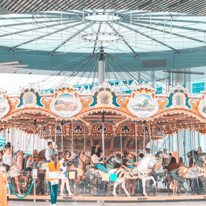 People riding a merry-go-round carousel during daytime, similar to the antique carousel at DelGrosso's Park in Tipton, PA