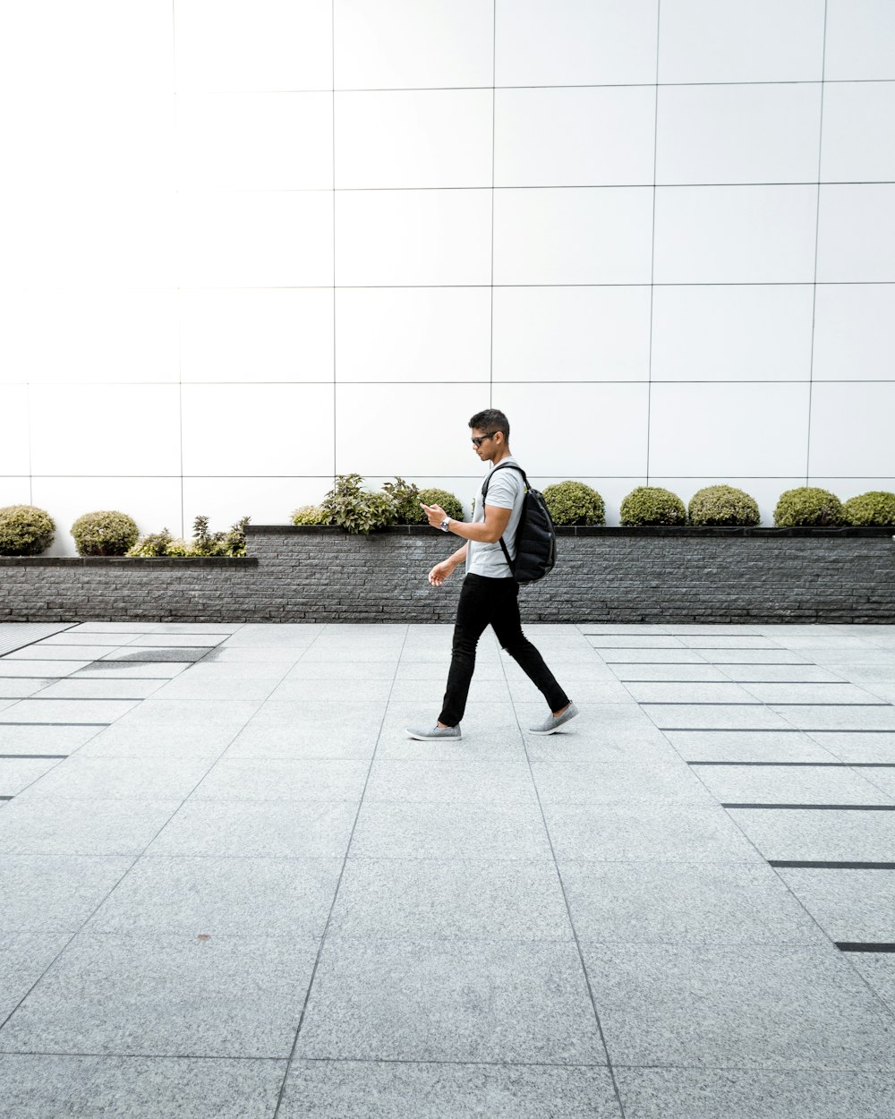 man with backpack using phone walking alone on pathway