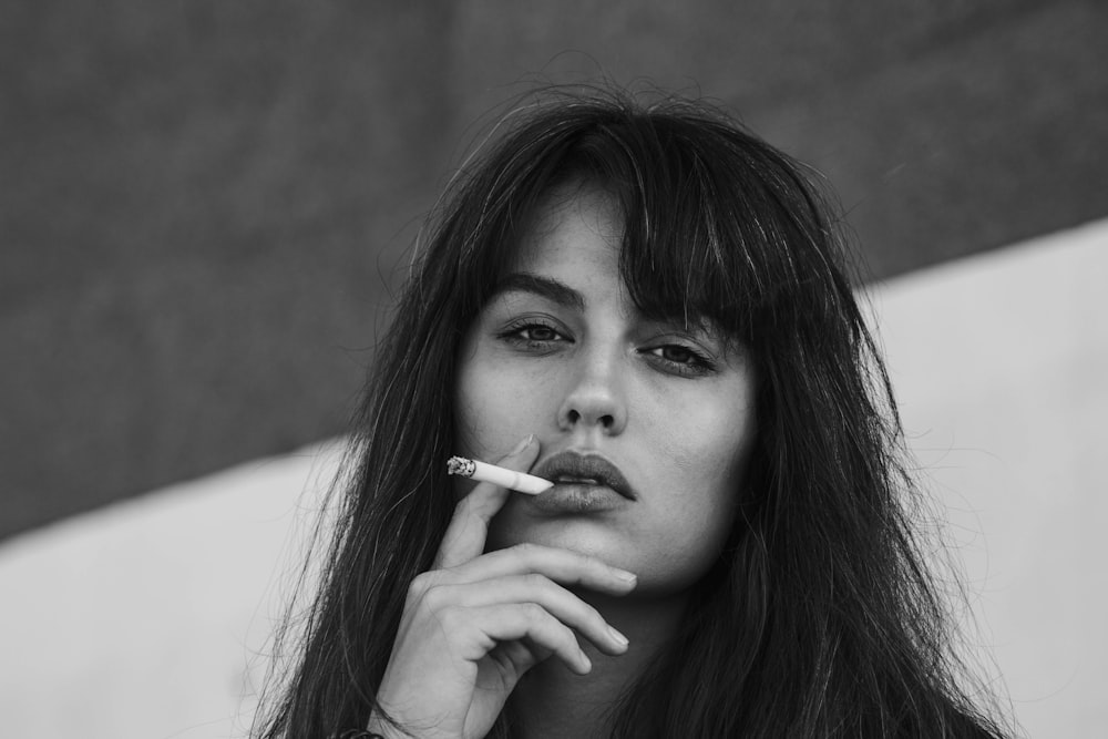 Photographie en niveaux de gris d’une femme fumant une cigarette