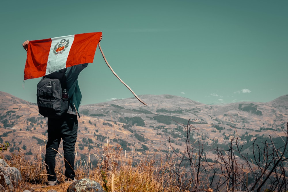 Hombre que lleva la bandera en la cima de un acantilado