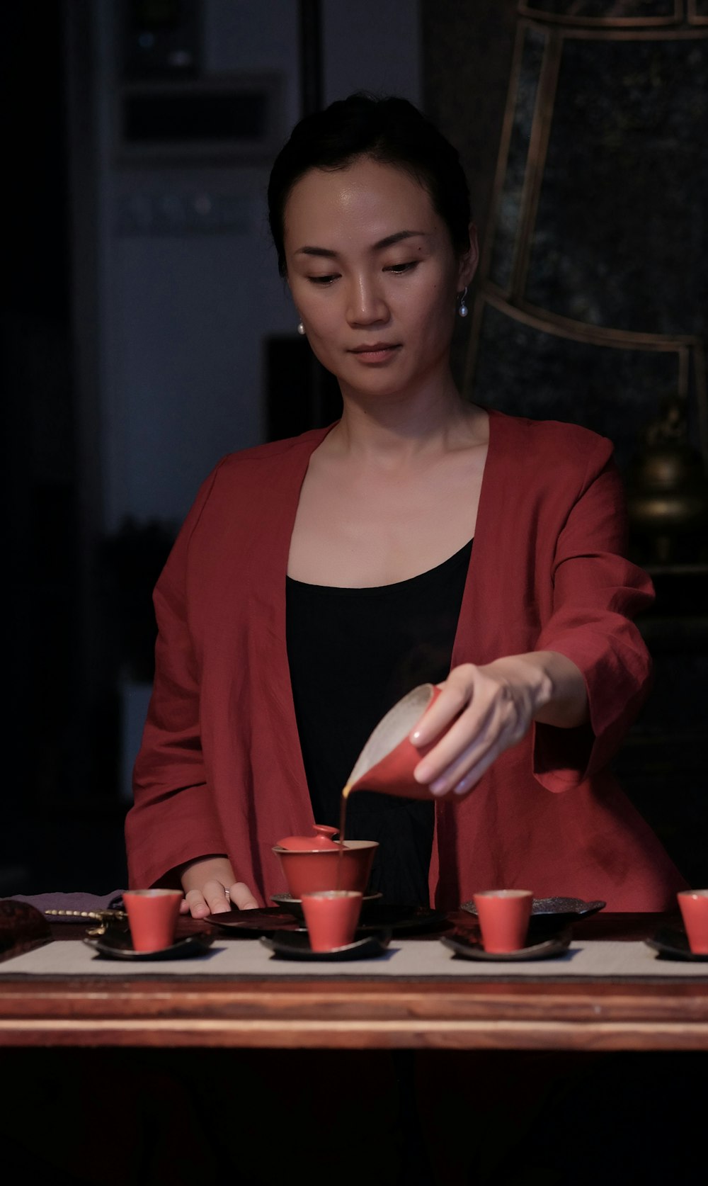 woman in red blazer pouring tea on teacup