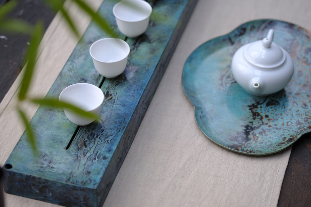 white ceramic teapot set on blue surface during daytime