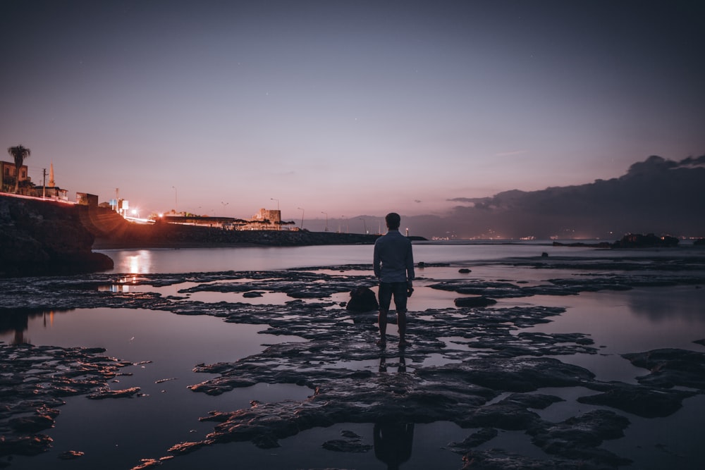 man standing on middle of beach in low tide