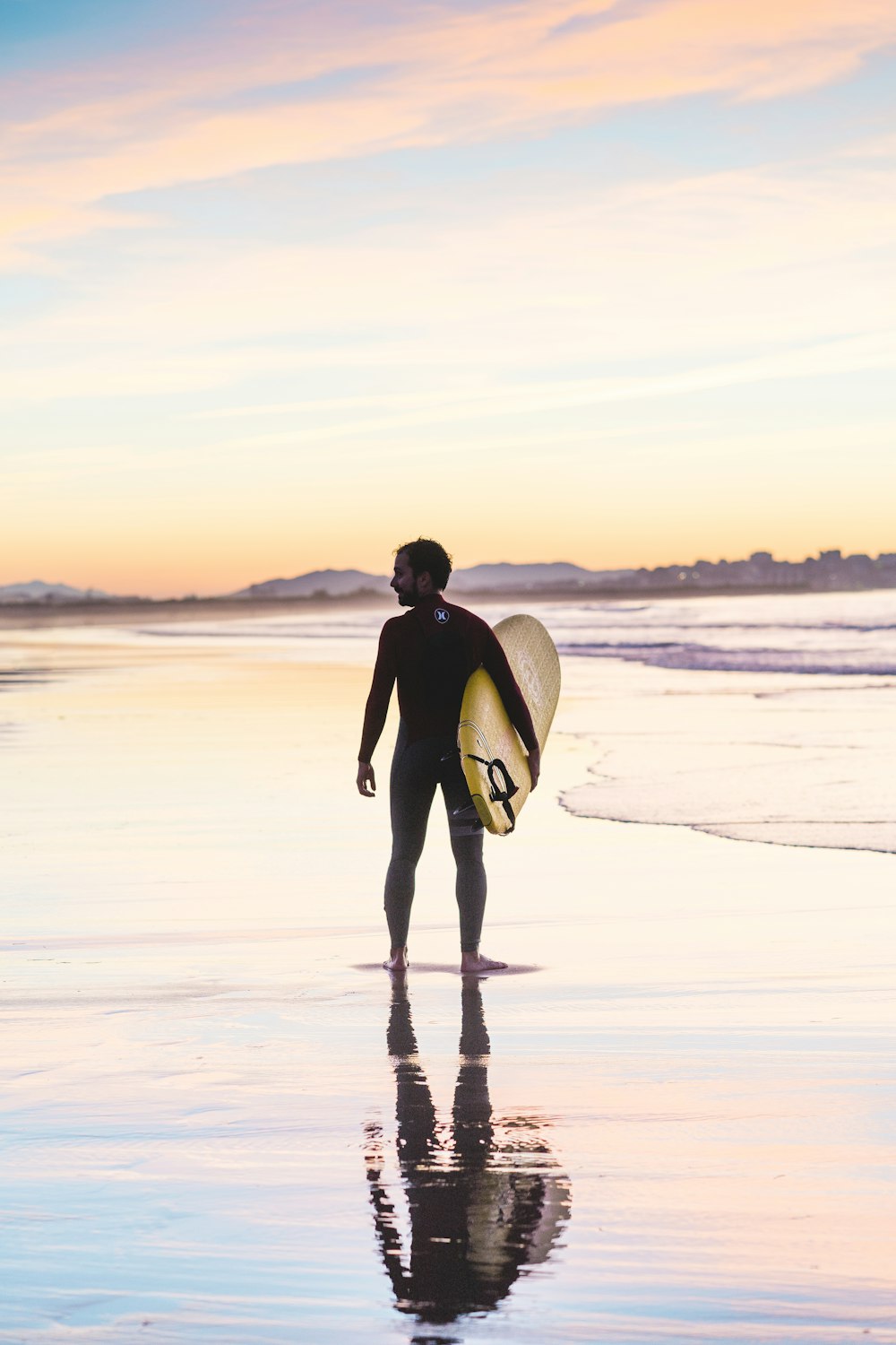 Mann mit Surfbrett, der am Ufer steht