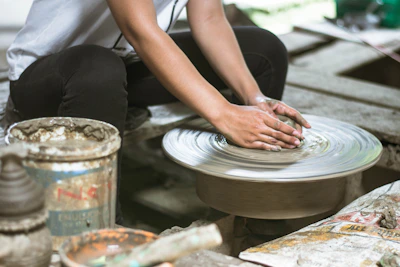 An artisan’s hands shaping clay on a pottery wheel, surrounded by colorful glazes.