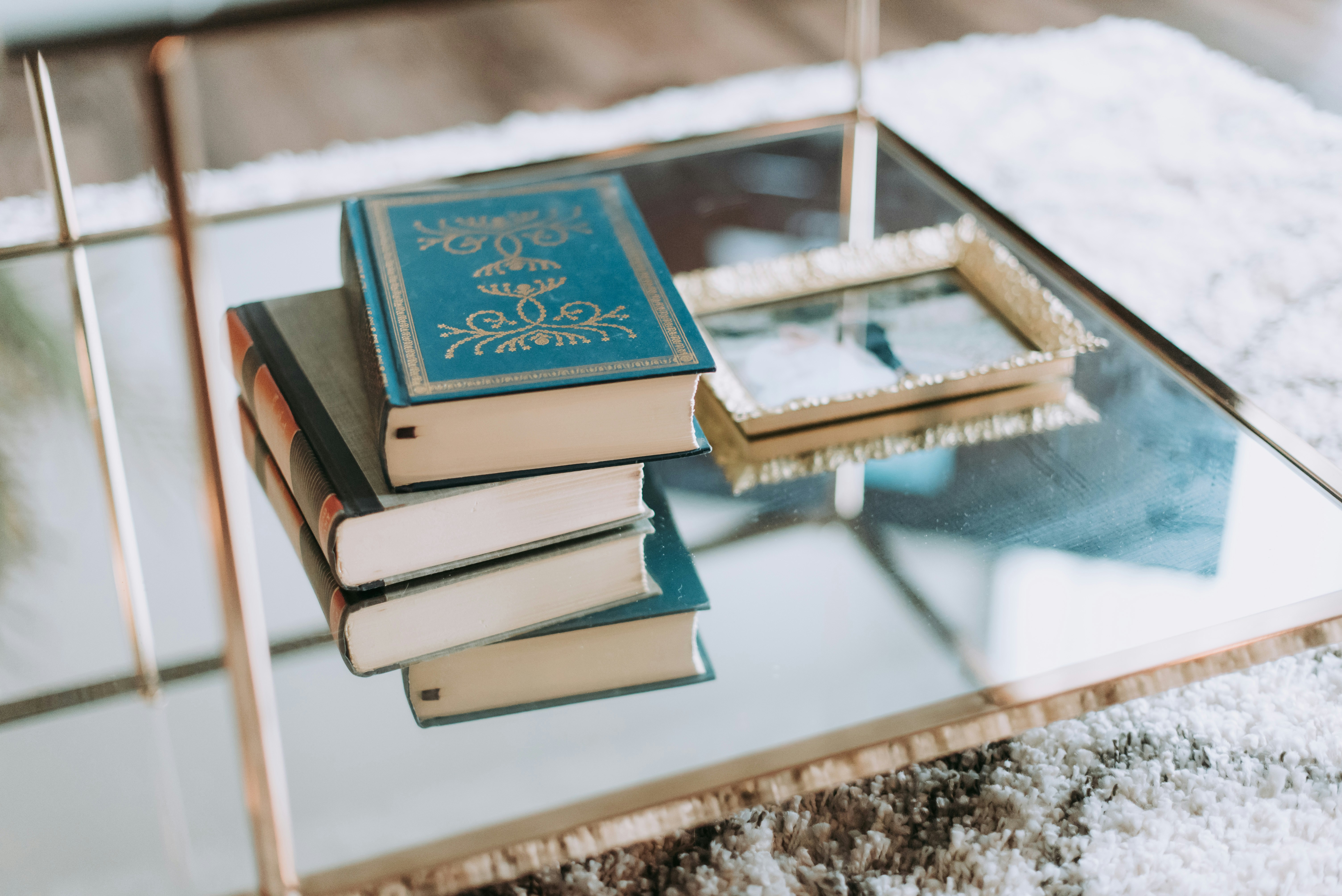 stacked decorative books on glass coffee table in cozy apartment