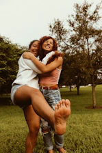 A smiling couple happily sharing a selfie together on their phone in a warm park setting.