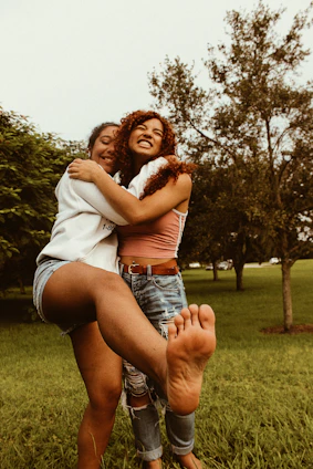 A smiling couple happily sharing a selfie together on their phone in a warm park setting.