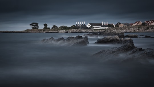landscape photography of houses near sea under dark clouds in Svaneke Denmark