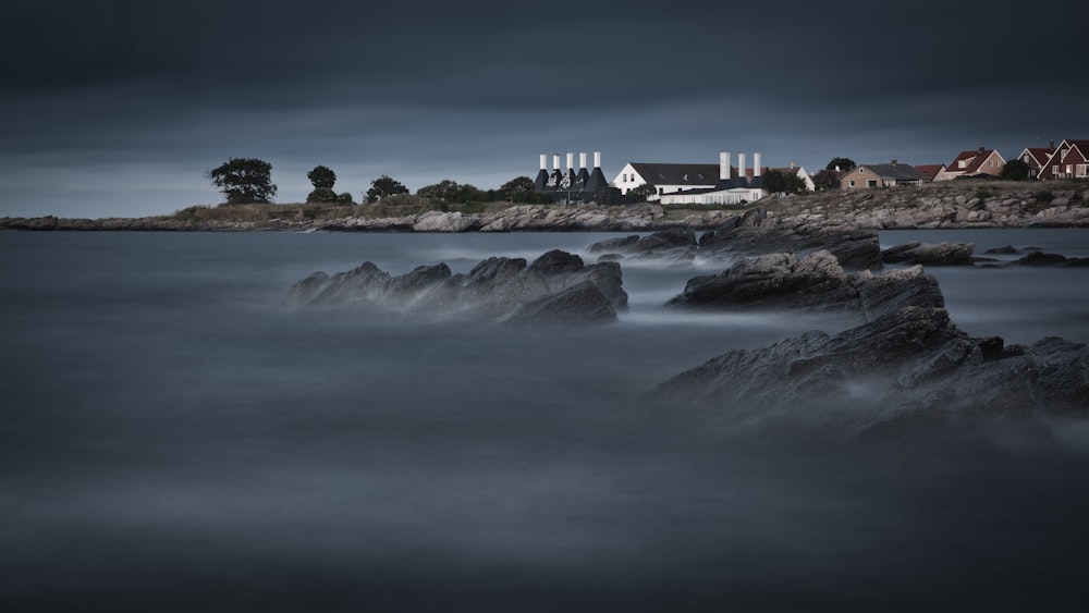 landscape photography of houses near sea under dark clouds