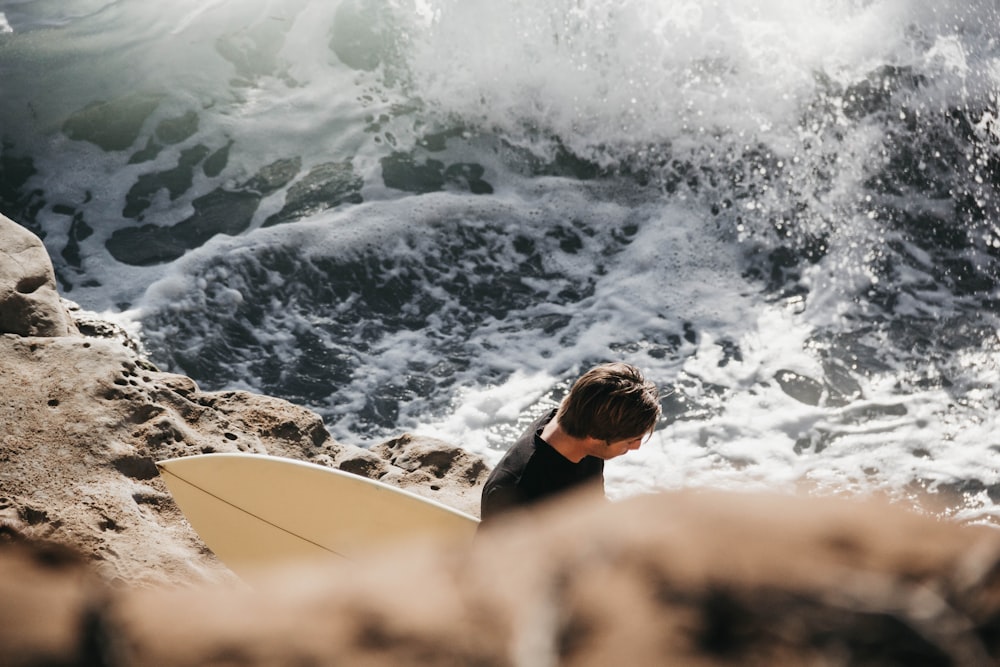 homme tenant une planche de surf au bord de la mer