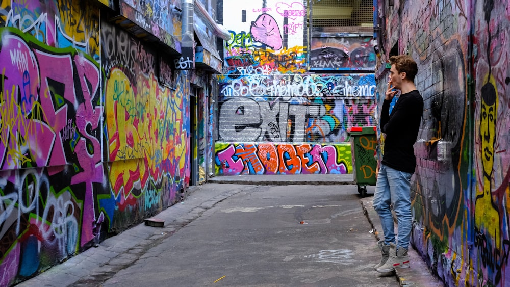 man leaning beside multi-colored wall