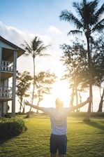A person standing confidently with arms wide open facing a sunrise symbolizing new beginnings.