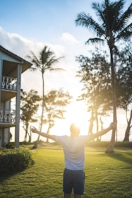 A person standing confidently with arms wide open facing a sunrise symbolizing new beginnings.