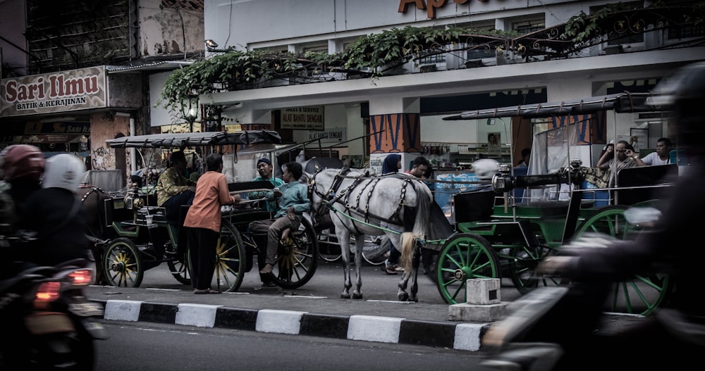 people standing and riding on carriage near store on road during daytime