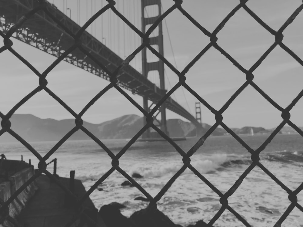 grayscale photo of chain linked fence across concrete bridge